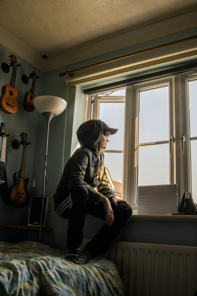 man in gray jacket sitting on chair beside window